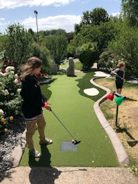 two children playing mini golf in a garden