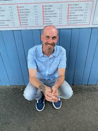 a man crouching down in front of a sign