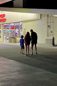 a group of people walking in front of a store at night